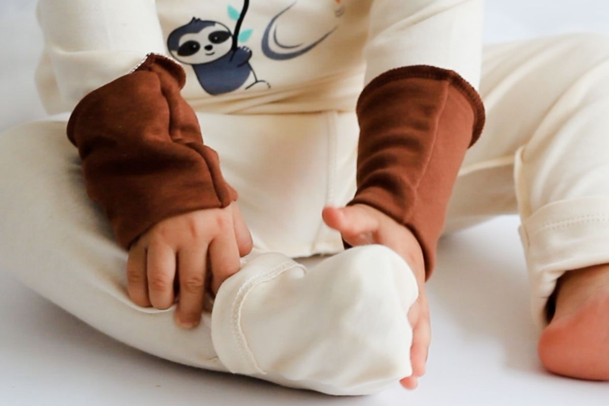 Kind trägt weiche Bio Pima Baumwollkleidung mit braunen Kratzschutzbündchen und Außennähten als Alternative zu Wolle bei Neurodermitis